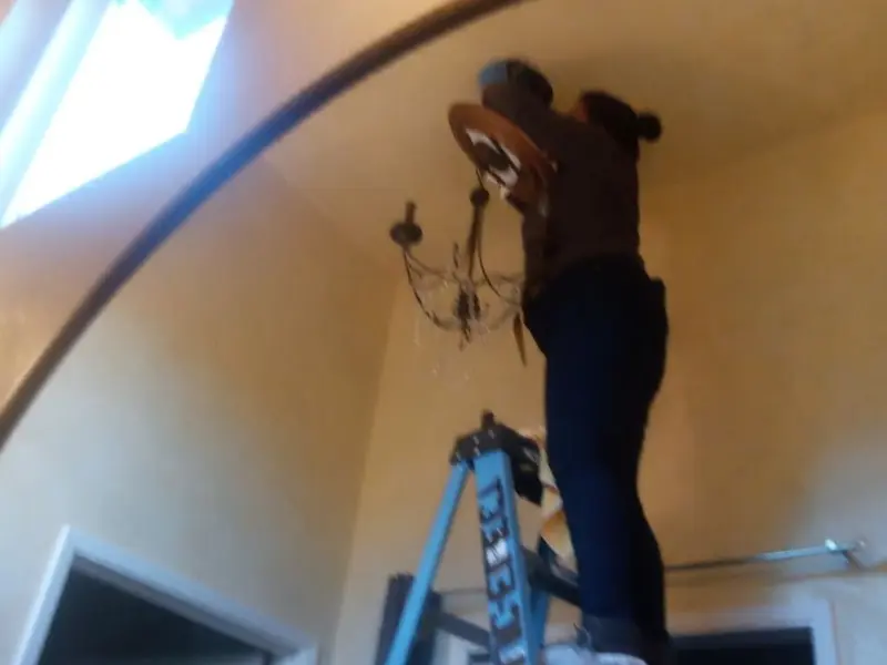 Electrician installing a chandelier in a Beekmantown residence